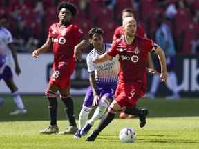 Le milieu de terrain du Toronto FC Michael Bradley déplace le ballon contre l'attaquant d'Orlando City Facundo Torres.