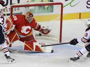 Jacob Markstrom des Flames de Calgary garde cette rondelle hors du filet avec le centre Ryan Nugent-Hopkins des Oilers d'Edmonton attaquant pendant la première période d'action alors que les Flames de Calgary accueillent les Oilers d'Edmonton dans le match 2 du deuxième tour des séries éliminatoires de la Coupe Stanley au Saddledome.  Vendredi 20 mai 2022. Brendan Miller/Postmedia