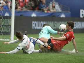 Le gardien du Toronto FC Alex Bono (25 ans) et le défenseur Shane O'Neill (27 ans) défendent contre le milieu de terrain des Whitecaps de Vancouver Ryan Gauld.