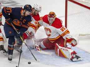 L'attaquant des Oilers d'Edmonton Connor McDavid affronte le défenseur des Flames de Calgary Noah Hanifin devant le gardien de but Jacob Markstrom lors du troisième match de leur série de premier tour au Rogers Place à Edmonton le dimanche 22 mai 2022.