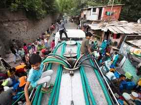 Les résidents utilisent des tuyaux pour recueillir l'eau potable d'un camion-citerne pendant une journée chaude à New Delhi le 3 mai 2022. La Cour suprême de l'Inde a statué que les citoyens ont le droit de refuser d'être vaccinés, et que les mesures de santé publique doivent être proportionnées à la risque.