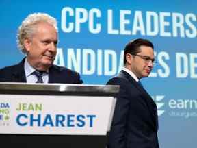 Pierre Poilievre, à droite, passe devant Jean Charest alors qu'il prend place sur scène lors du débat à la direction des conservateurs à Ottawa, le jeudi 5 mai 2022.