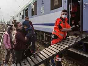 Des enfants traités pour un cancer et leurs familles montent à bord d'un train médical spécial à la gare de Medyka, en Pologne, après avoir traversé la frontière ukrainienne.