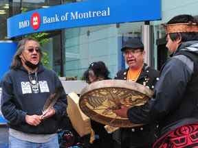 Maxwell Johnson (à gauche) devant la succursale de la rue Burrard de la Banque de Montréal à Vancouver le 5 mai 2022.