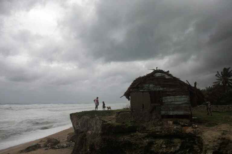 People stand in front of their home overlooking the sea as Tropical Storm Isaac approaches in Barahona, Dominican Republic, Friday, Aug. 24, 2012. Tropical Storm Isaac strengthened slightly as it spun toward the Dominican Republic and vulnerable Haiti on Friday, threatening to bring punishing rains but unlikely to gain enough steam to strike as a hurricane. (AP Photo/Ricardo Arduengo)