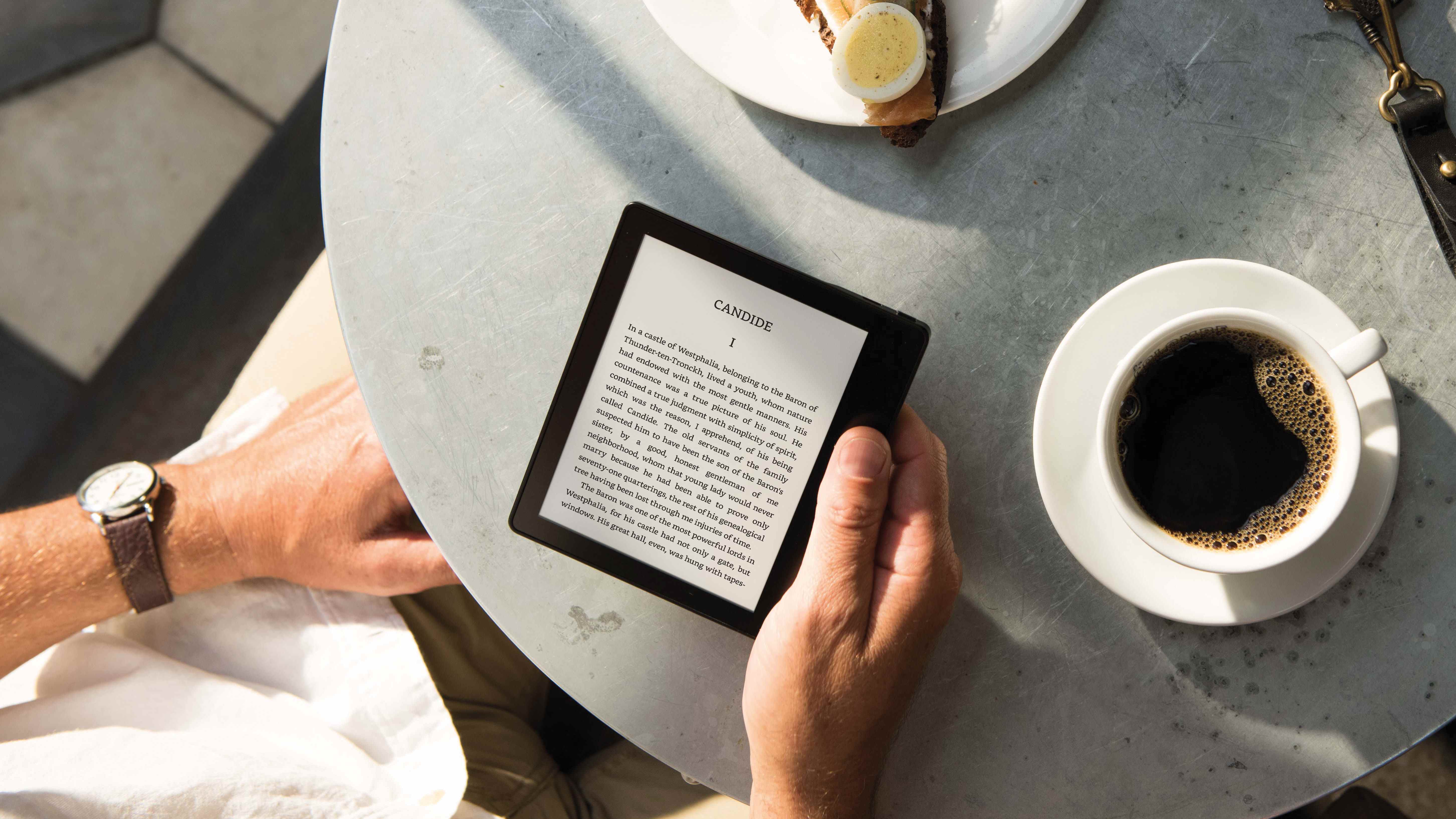 Le Kindle Oasis est lu pendant que quelqu'un boit du café à une table