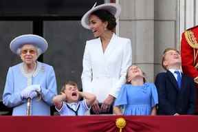 Le prince Louis tient ses oreilles alors qu'il se tient à côté de la reine Elizabeth, sa mère Catherine, la duchesse de Cambridge et les frères et sœurs la princesse Charlotte et le prince George pour assister à un défilé aérien spécial depuis le balcon du palais de Buckingham le 2 juin 2022. (Photo de DANIEL LEAL/AFP via Getty Images)