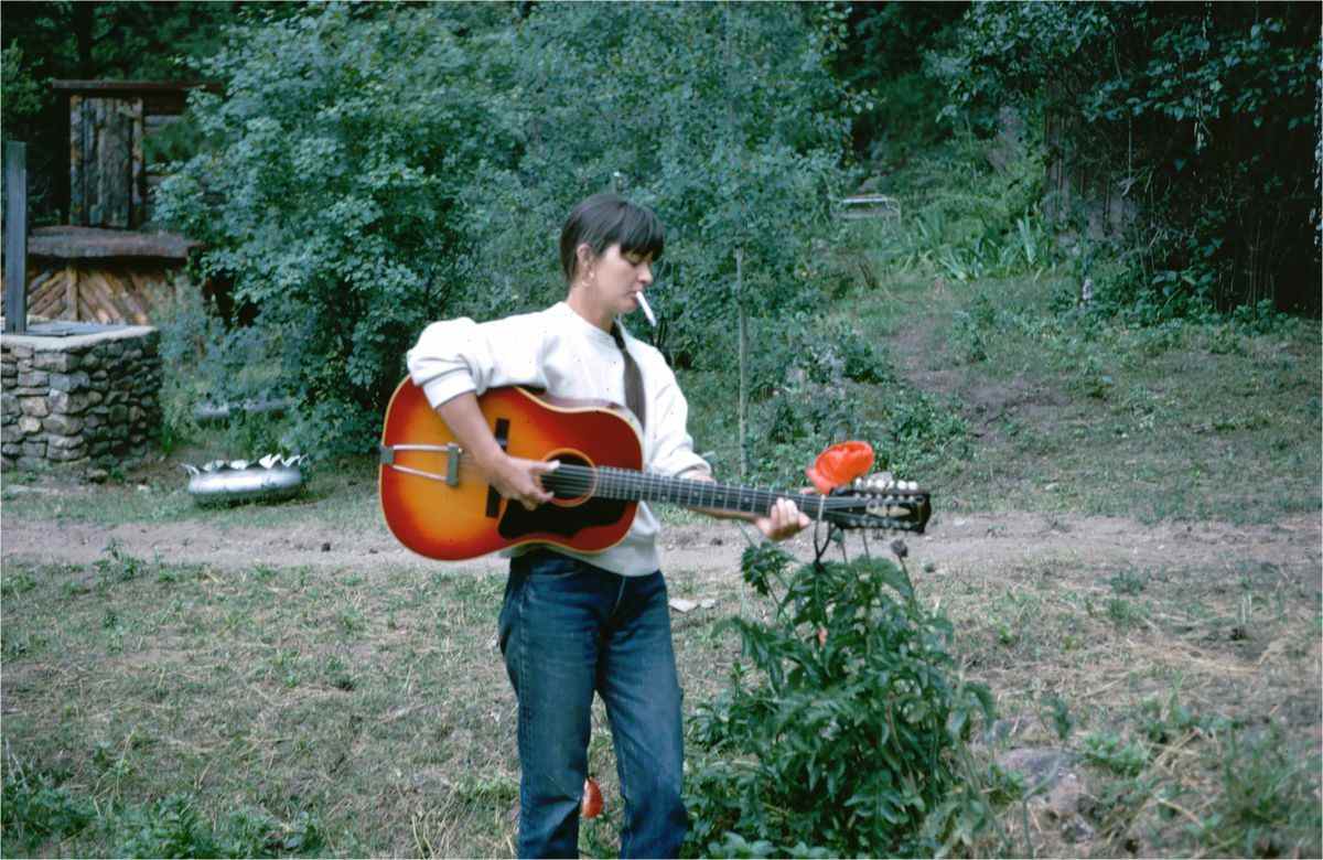 Karen Dalton jouant de la guitare et tenant une cigarette entre ses lèvres dans le documentaire Karen Dalton : In My Own Time.