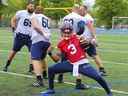 Le quart-arrière Vernon Adams a posé pour un photographe devant un groupe de joueurs de ligne offensive lors du camp d'entraînement des Alouettes la semaine dernière.