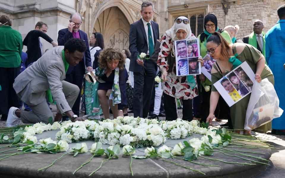 Les gens portent des photos d'êtres chers perdus alors qu'ils déposent des fleurs - WPA Pool/Getty Images Europe