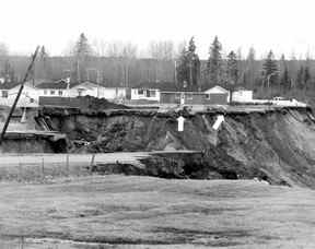 Un désastre frappe la petite communauté de Saint-Jean-Vienney dans la région du Lac Saint-Jean le 4 mai 1971. Cette photo, publiée dans la Gazette de Montréal le 6 mai 1971, montre deux voitures perchées précairement sur le bord du talus gauche par le glissement de terrain (voir flèches).