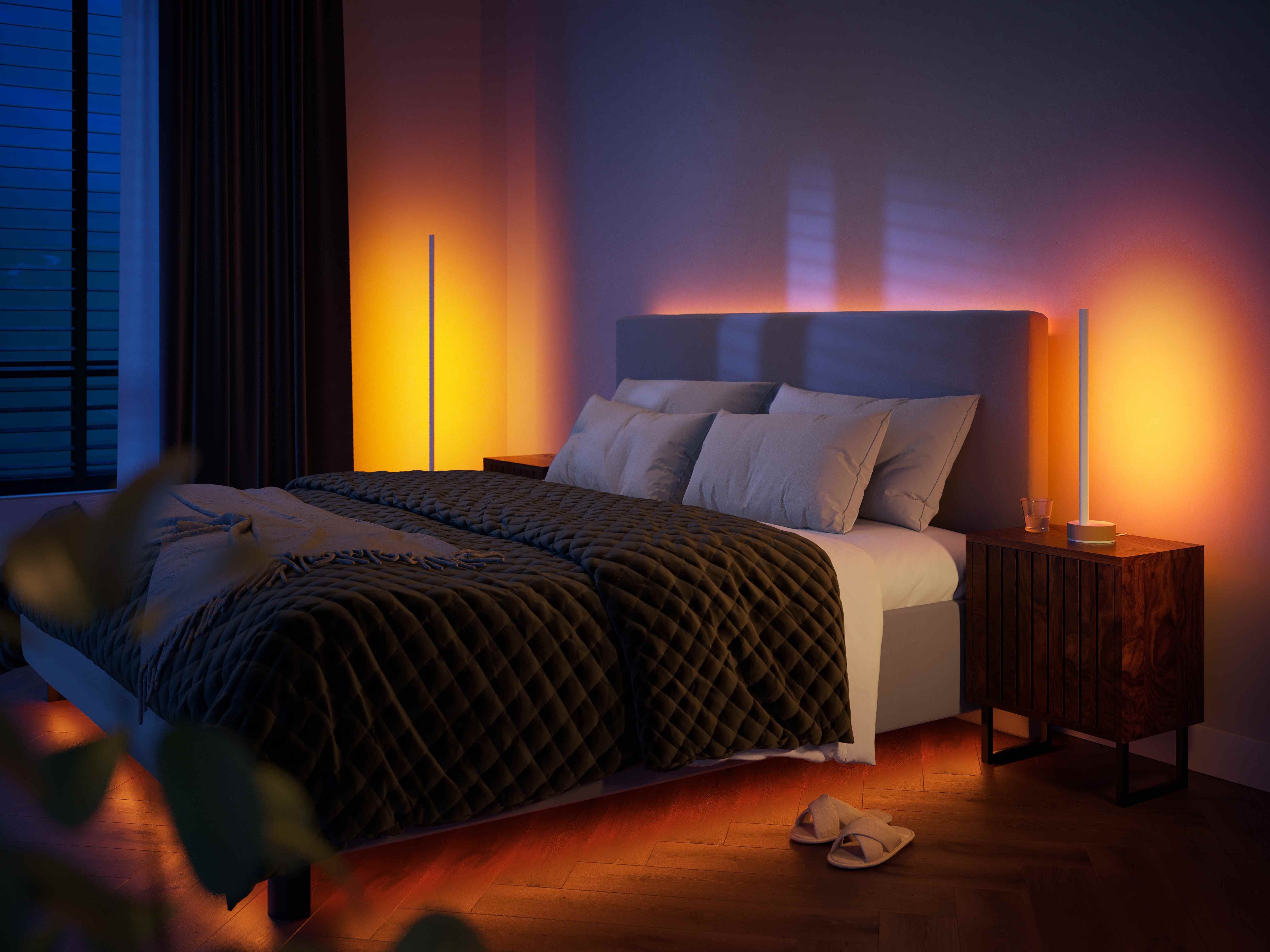 une photo de la lampe dégradée Philips Hue Signe en chêne dans une chambre