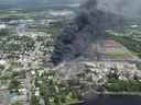 De la fumée s'élève des wagons transportant du pétrole brut après avoir déraillé au centre-ville de Lac-Mégantic le samedi 6 juillet 2013. Lac-Mégantic célèbre le septième anniversaire d'une tragique catastrophe ferroviaire qui a coûté la vie à 47 personnes en inaugurant un espace commémoratif prévu de longue date .