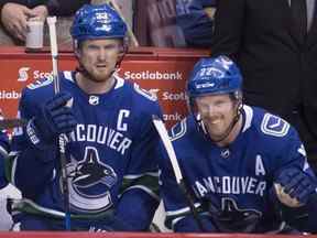 Les Canucks de Vancouver Henrik Sedin (33 ans) et son frère et coéquipier Daniel Sedin (22 ans) regardent depuis le banc lors de la deuxième période d'action de la LNH contre les Golden Knights de Vegas au Rogers Arena de Vancouver, le mardi 3 avril 2018.