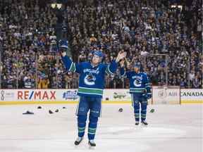 Daniel Sedin et Henrik Sedin, à droite, des Canucks de Vancouver saluent les partisans après avoir disputé le dernier match à domicile de leur carrière dans la LNH le 5 avril 2018 au Rogers Arena de Vancouver.