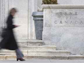 Une femme passe devant l'édifice de la Banque du Canada à Ottawa.