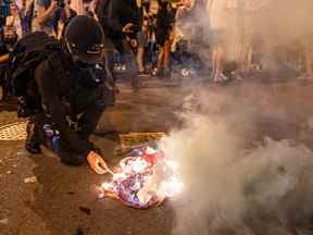 Un manifestant allume une cigarette sur un drapeau américain en feu, alors qu'il marche avec des militants du droit à l'avortement à Washington, DC, le 24 juin.