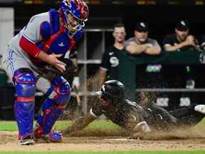 Tim Anderson des Chicago White Sox glisse à la maison pour marquer en 11e manche contre Alejandro Kirk # 30 des Blue Jays de Toronto au Guaranteed Rate Field le 21 juin 2022 à Chicago, Illinois.