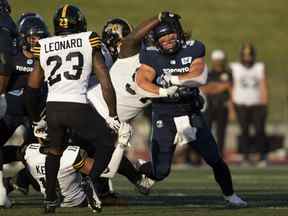 Le porteur de ballon des Argonauts AJ Ouellette est plaqué par le plaqueur défensif des Tiger-Cats de Hamilton Ted Laurent lors de la première moitié de l'action de football de pré-saison de la LCF à Guelph, en Ontario, le vendredi 3 juin 2022.