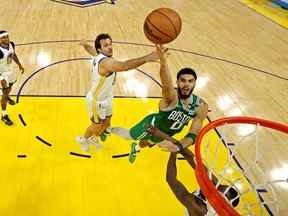 L'attaquant des Boston Celtics Jayson Tatum (0) tire le ballon contre l'attaquant des Golden State Warriors Draymond Green (23) lors du deuxième match de la finale de la NBA 2022 au Chase Center.