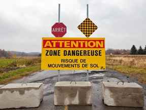 Un panneau d'avertissement et un blocus de rue sont visibles près de la scène d'un glissement de terrain dans la ville de St. Jude le 25 octobre 2010.