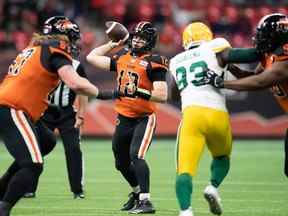 Le quart-arrière des Lions de la Colombie-Britannique, Nathan Rourke (12 ans), passe alors que Phillip Norman (50 ans) retient Kwaku Boateng (93 ans) des Elks d'Edmonton lors de la première moitié d'un match de football de la LCF à Vancouver, le vendredi 19 novembre 2021.