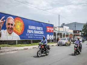 Les gens passent devant une bannière accueillant le pape François à Goma, en République démocratique du Congo, le vendredi 10 juin 2022. Les plans continuent d'aller de l'avant pour la visite du pape François au Canada, même si le pontife annule un voyage prévu en Afrique sur ordre des médecins.