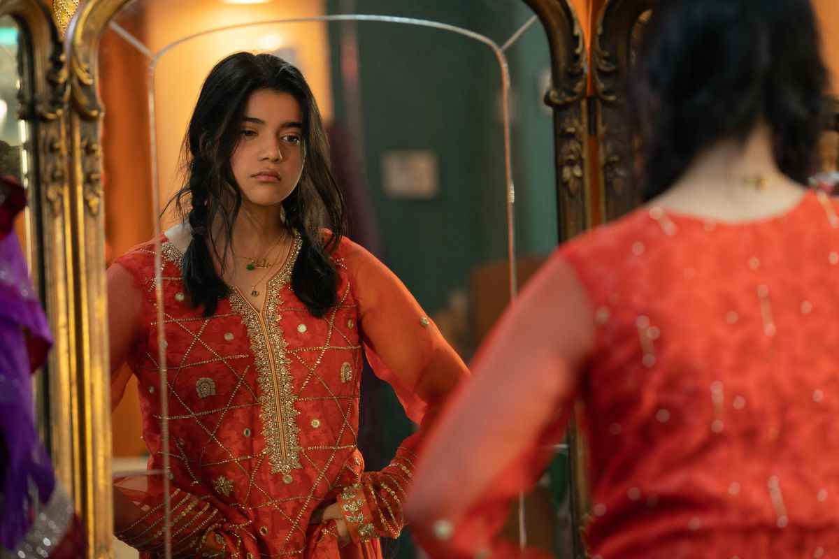 kamala dans une tenue pakistanaise traditionnelle orange, regardant dans un miroir