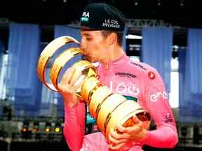 Le coureur australien de l'équipe Bora, Jai Hindley, célèbre les baisers "Trophée Senza Fine" trophée du vainqueur de la course sur le podium après avoir remporté la course cycliste Giro dItalia 2022, après la dernière étape, un contre-la-montre individuel de 17,4 km à Vérone le 29 mai 2022. (Photo de Luca Bettini / AFP)