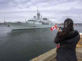 Une femme prend une photo alors que le NCSM Halifax quitte Halifax le 19 mars.