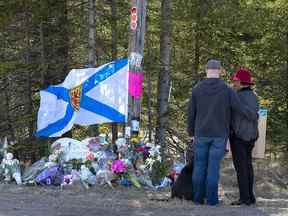 Un couple rend hommage à un barrage routier à Portapique, en Nouvelle-Écosse, le 22 avril 2020. Le gendarme qui a dirigé la première réponse à la fusillade de masse en Nouvelle-Écosse a témoigné lundi que ses plans pour bloquer la voie d'évacuation du tueur avaient été renversés par un subordonné. "malentendu," et un écrasement de tâches concurrentes.