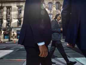 Un groupe d'hommes marche le long de la rue Wellington dans le quartier financier de Toronto, le 29 septembre 2021.