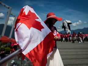 Une femme agite un drapeau canadien tout en arborant une tenue patriotique lors des célébrations de la fête du Canada à Vancouver le 1er juillet 2019.