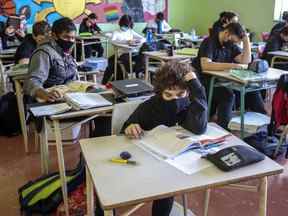 Des élèves masqués lisent à leur pupitre dans une école de Montréal.