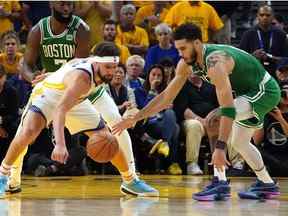 Le gardien des Golden State Warriors Klay Thompson et l'attaquant des Boston Celtics Jayson Tatum se battent pour un ballon lâche au cours de la seconde mi-temps du premier match de la finale de la NBA 2022 au Chase Center.