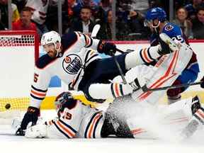 L'ailier droit des Oilers d'Edmonton Josh Archibald (15 ans) entre en collision avec le gardien de but Mikko Koskinen (19 ans) après avoir accordé un but en deuxième période lors du premier match de la finale de la Conférence de l'Ouest des séries éliminatoires de la Coupe Stanley 2022 au Ball Arena.