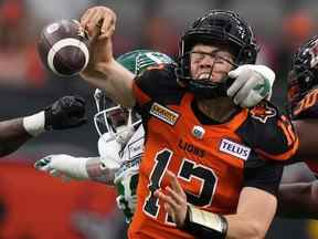 Le quart-arrière des Lions de la Colombie-Britannique Nathan Rourke est limogé par Garrett Marino des Roughriders de la Saskatchewan, arrière, et tâtonne le ballon pendant la première moitié d'un match de football de pré-saison de la LCF à Vancouver, en Colombie-Britannique, le vendredi 3 juin 2022.