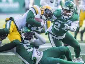 Le receveur large des Elks d'Edmonton Earnest Edwards (81) est plaqué par le demi défensif des Roughriders de la Saskatchewan Loucheiz Purifoy (5) et le demi défensif des Roughriders de la Saskatchewan Damon Webb (24) lors de la première mi-temps de l'action de football de la LCF à Regina, le samedi 13 novembre 2021.