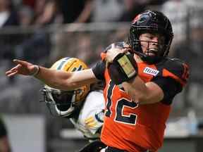 Le quart-arrière des Lions de la Colombie-Britannique Nathan Rourke est poussé hors des limites par Jalen Collins des Elks d'Edmonton alors qu'il court avec le ballon pendant la première moitié du match de football de la LCF à Vancouver, le samedi 11 juin 2022.