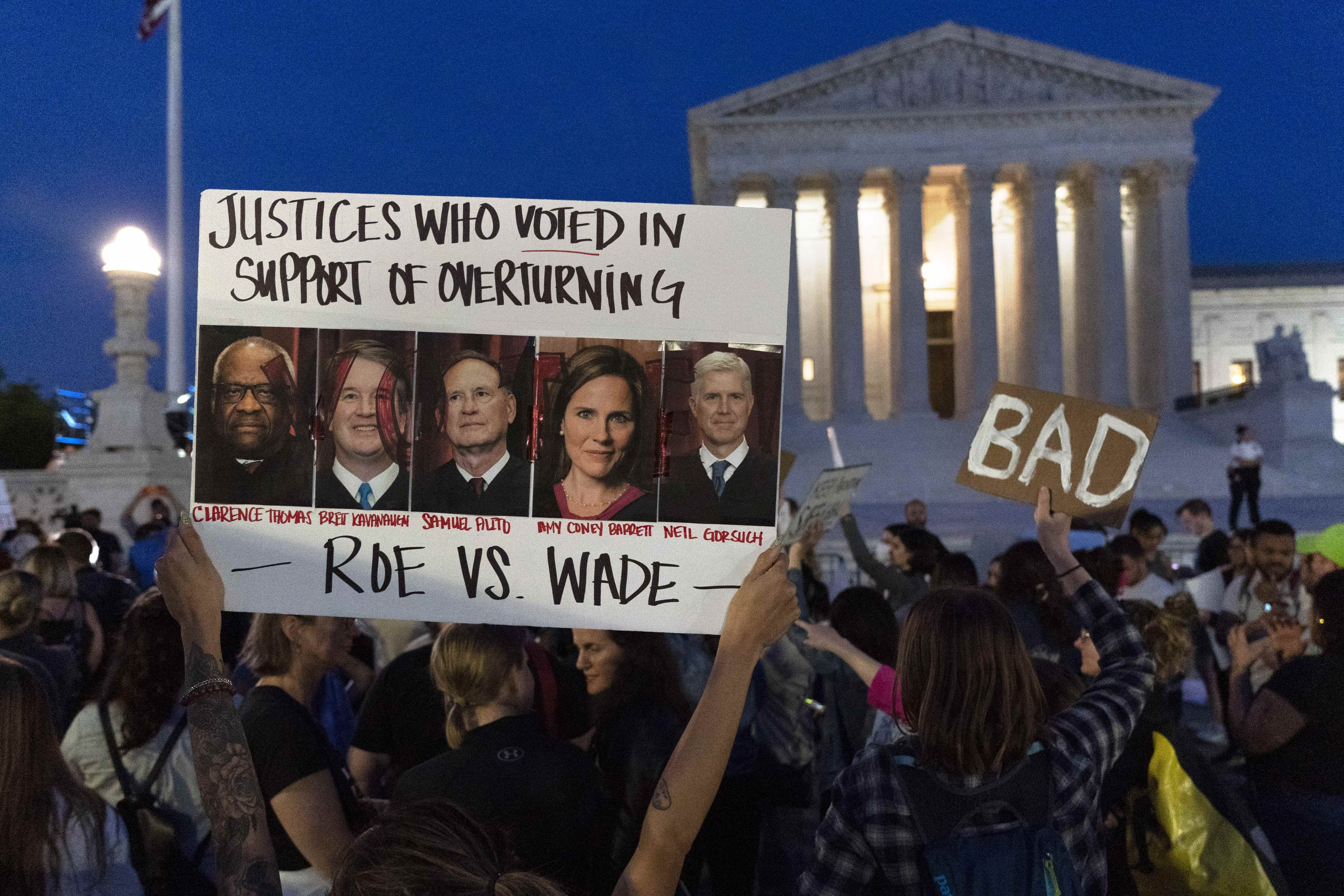 Nikki Tran de Washington, brandit une pancarte avec des photos des juges de la Cour suprême Clarence Thomas, Brett Kavanaugh, Samuel Alito, Amy Coney Barrett et Neil Gorsuch, alors que des manifestants protestent devant la Cour suprême des États-Unis, le mardi 3 mai 2022, à Washington.  Un projet d'avis suggère que la Cour suprême des États-Unis pourrait être sur le point d'annuler l'affaire historique Roe contre Wade de 1973 qui a légalisé l'avortement dans tout le pays, selon un rapport Politico publié lundi.  Quel que soit le résultat, le rapport Politico représente une violation extrêmement rare du processus de délibération secrète de la cour, et sur une affaire d'une importance capitale.  (AP Photo/Jacquelyn Martin)