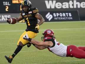 Le demi défensif des Tiger-Cats de Hamilton Frankie Williams (1) est attaqué par l'arrière des Stampeders de Calgary Elliot Graham (37) lors de la première mi-temps d'un match de football de la LCF à Hamilton, en Ontario.  le vendredi 17 septembre 2021.