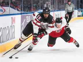 Le Canadien Shane Wright (15) et l'Autrichien Tobias Sablattnig (12) se battent pour la rondelle lors de l'action du Championnat mondial de hockey junior de l'IIHF à Edmonton le 28 décembre 2021. Le choix consensuel pour le premier choix au repêchage de la LNH cette année est Wright des Frontenacs de Kingston, écrit Jack Todd.