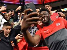 Le milieu de terrain canadien Alphonso Davies (à droite) signe des autographes et prend des photos avec des fans après le match de football de la Concacaf Nations League entre le Canada et Curaçao au stade BC Place à Vancouver le 9 juin 2022.