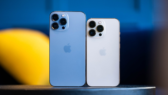 Un iPhone 13 Pro Mac bleu et un iPhone 13 Pro doré côte à côte sur une table avec leurs caméras arrière face à nous.