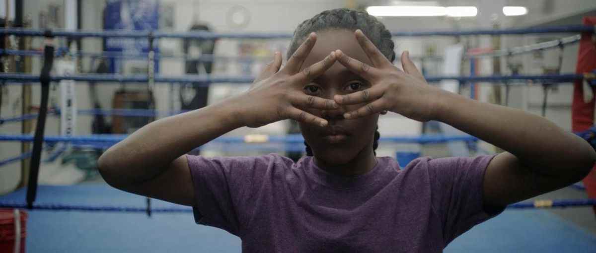 Royalty Hightower regarde à travers ses doigts devant un ring de boxe dans The Fits.