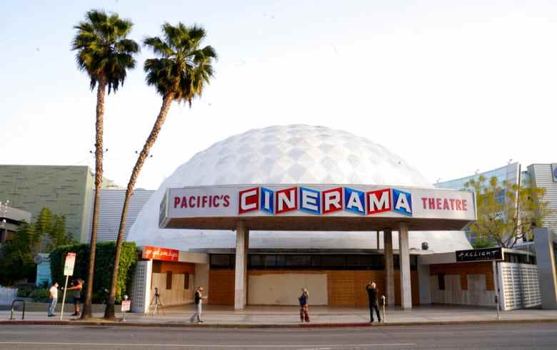 Bystanders gather outside the Cinerama Dome movie theater, Monday, April 12, 2021, in Los Angeles. Pacific Theaters, which operates some 300 screens in California, including the beloved ArcLight theaters and the historic Cinerama Dome in Hollywood, said Monday that it will not be reopening. Fans, including numerous actors, took to social media to share memories of the theater chain and lobby for it to be saved. (AP Photo/Chris Pizzello)