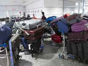 Un passager cherche ses bagages parmi une pile de bagages non réclamés à l'aéroport Pierre Elliott Trudeau de Montréal, le 29 juin 2022.