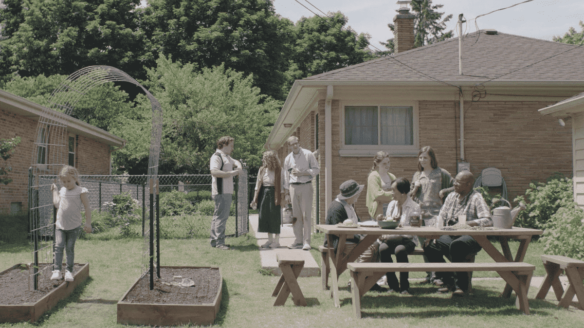 Joe Pera et Sarah debout et regardant un rassemblement de quartier