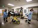 Des ambulanciers paramédicaux et des travailleurs de la santé transfèrent un patient de l'unité de soins intensifs de l'hôpital Humber River à une ambulance aérienne en attente alors que l'hôpital libère de l'espace dans leur unité de soins intensifs, à Toronto, Ontario, Canada, le 28 avril 2021.