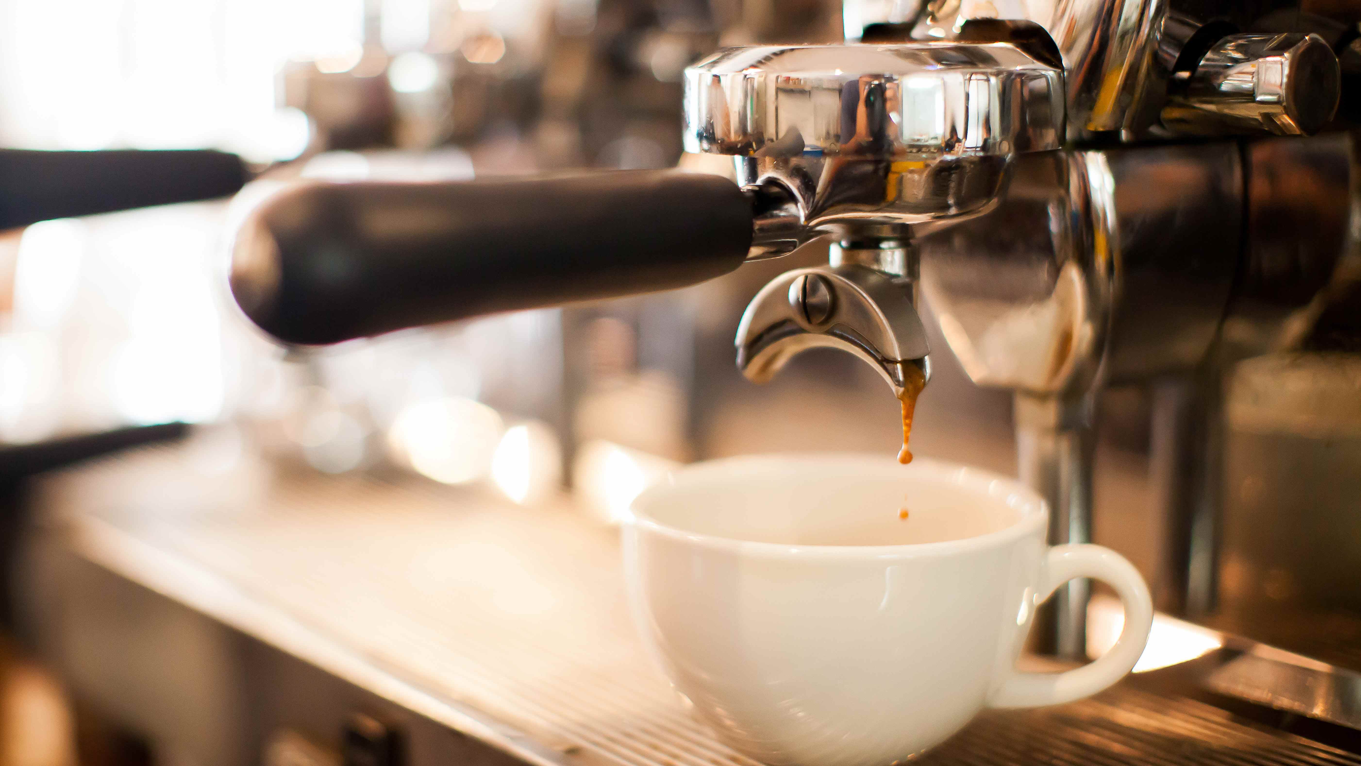 Une tasse de café sur une machine à expresso et du café qui commence à infuser